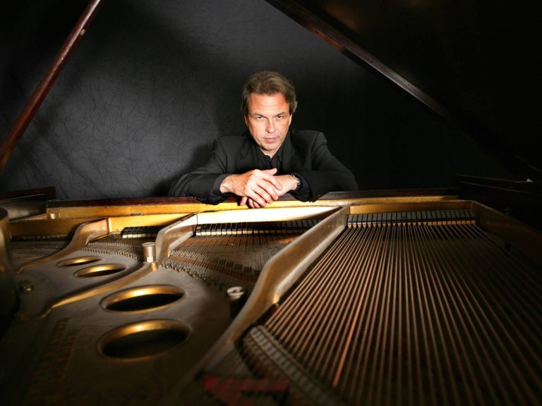 David Hazeltine recolzat damunt la tapa d'un piano de cua, en la imatge que fa servir el Jamboree per al concert del 23 d'octubre