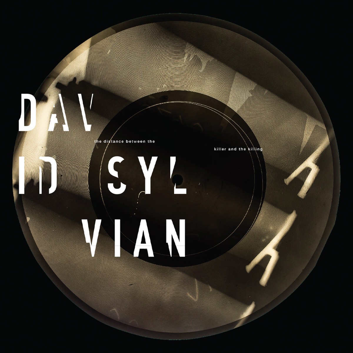 La portada de «The Distance Between The Killer And The Killing», de David Sylvian, amb el disc de vinil il·lustrat i el nom partit en tres línies