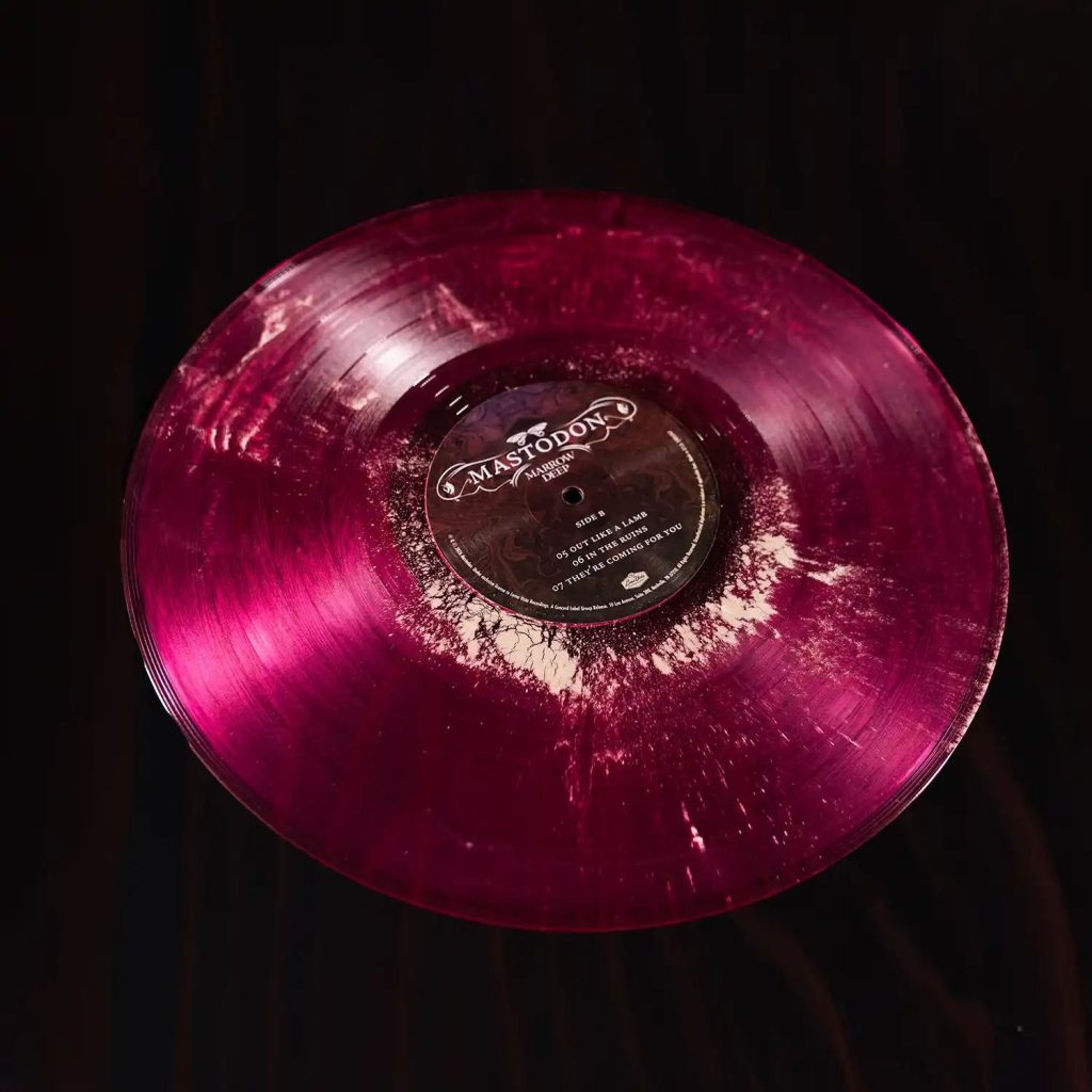 Cara B del vinil magenta de «Marrow Deep» de Mastodon, amb els grumolls blancs de pols d'os fòssil repartits pel solc