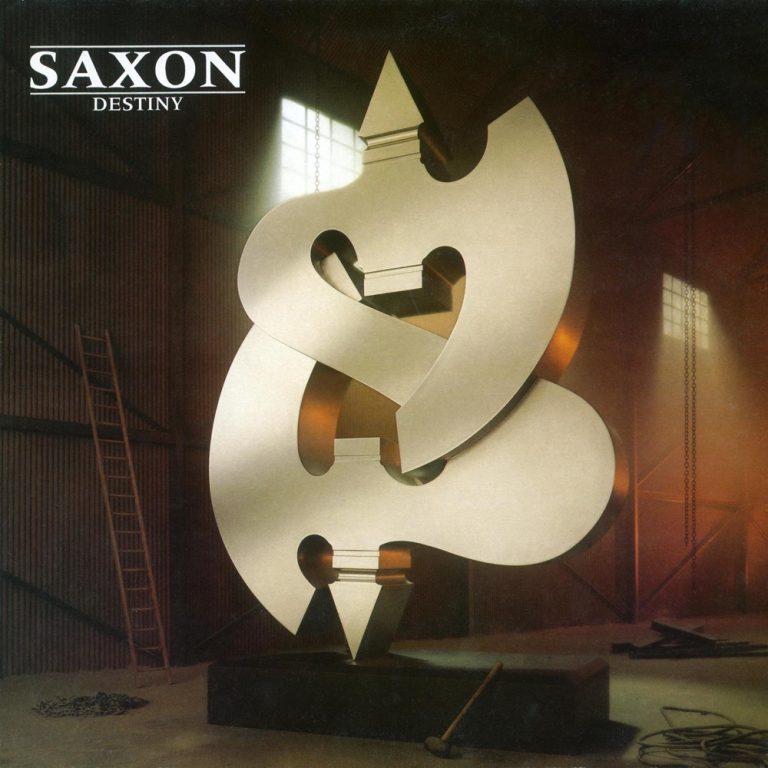 Portada de «Destiny», de Saxon: una escultura metàl·lica platejada en forma de doble essa, rematada amb dues puntes de fletxa, dins d'una nau industrial amb una escala de fusta i una maça a terra
