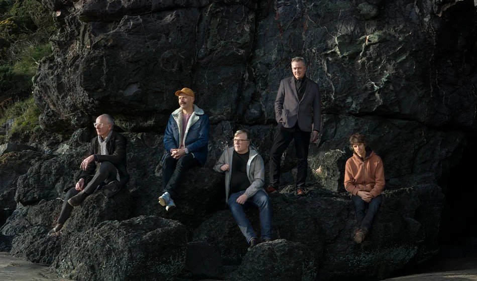 Els cinc membres de Teenage Fanclub asseguts sobre unes roques, en la imatge que fa servir el Razzmatazz per al concert del 17 d'octubre