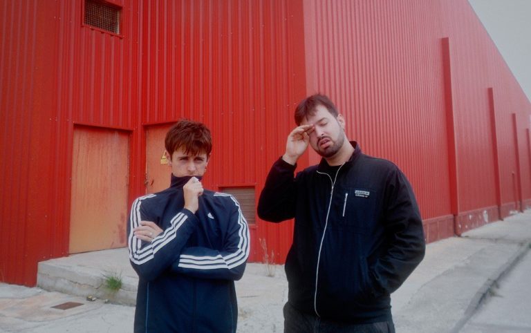 Daniel Sabater i Félix Esteban, el duo Rata, drets davant d'una nau industrial pintada de vermell